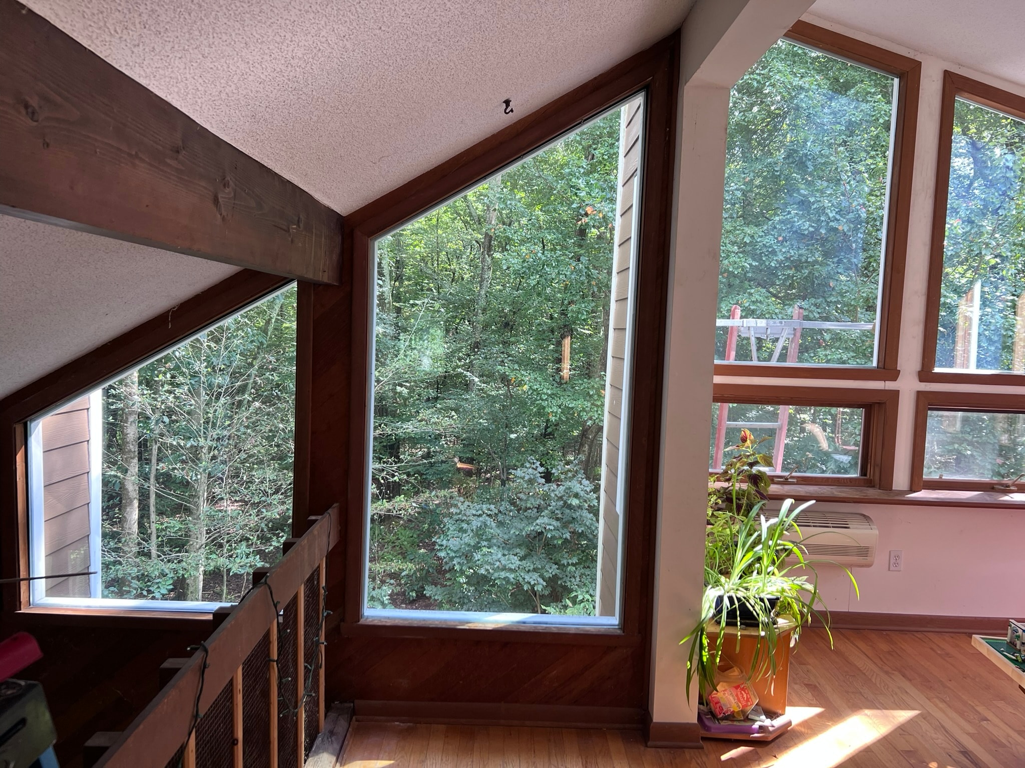 Interior view of original oversized fixed glass panels with dark wood framing — before replacement