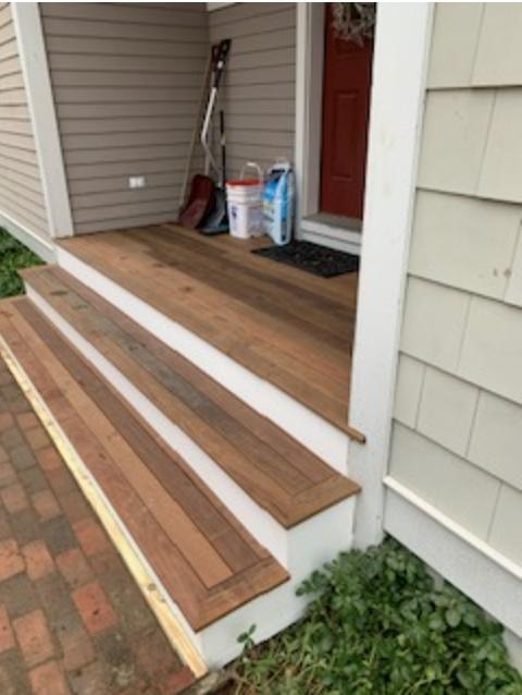 Completed front porch stair reframe — mahogany hardwood treads with white Azek risers, angled view showing full stair run and porch landing, Eastern Connecticut