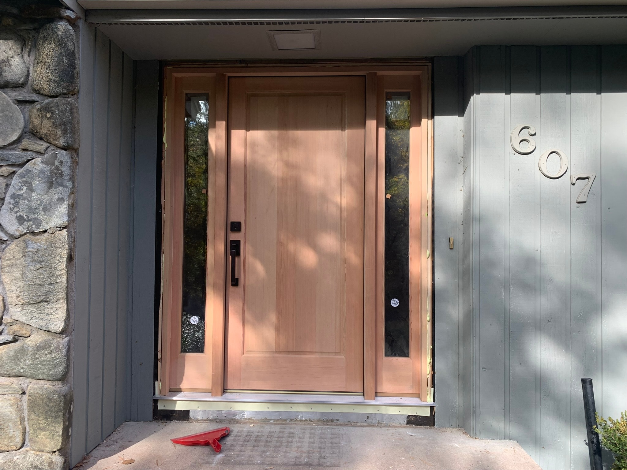 Custom craftsman-style solid wood entry door with dual sidelights and matte black hardware — exterior install, Eastern Connecticut