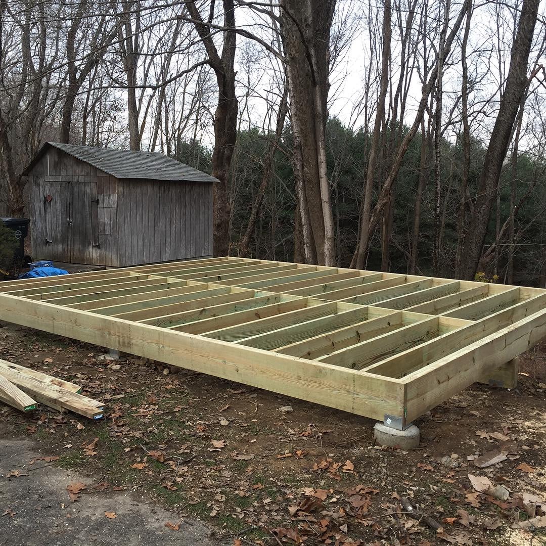 Woodworking shop floor frame on concrete piers — pressure-treated joists and rim board