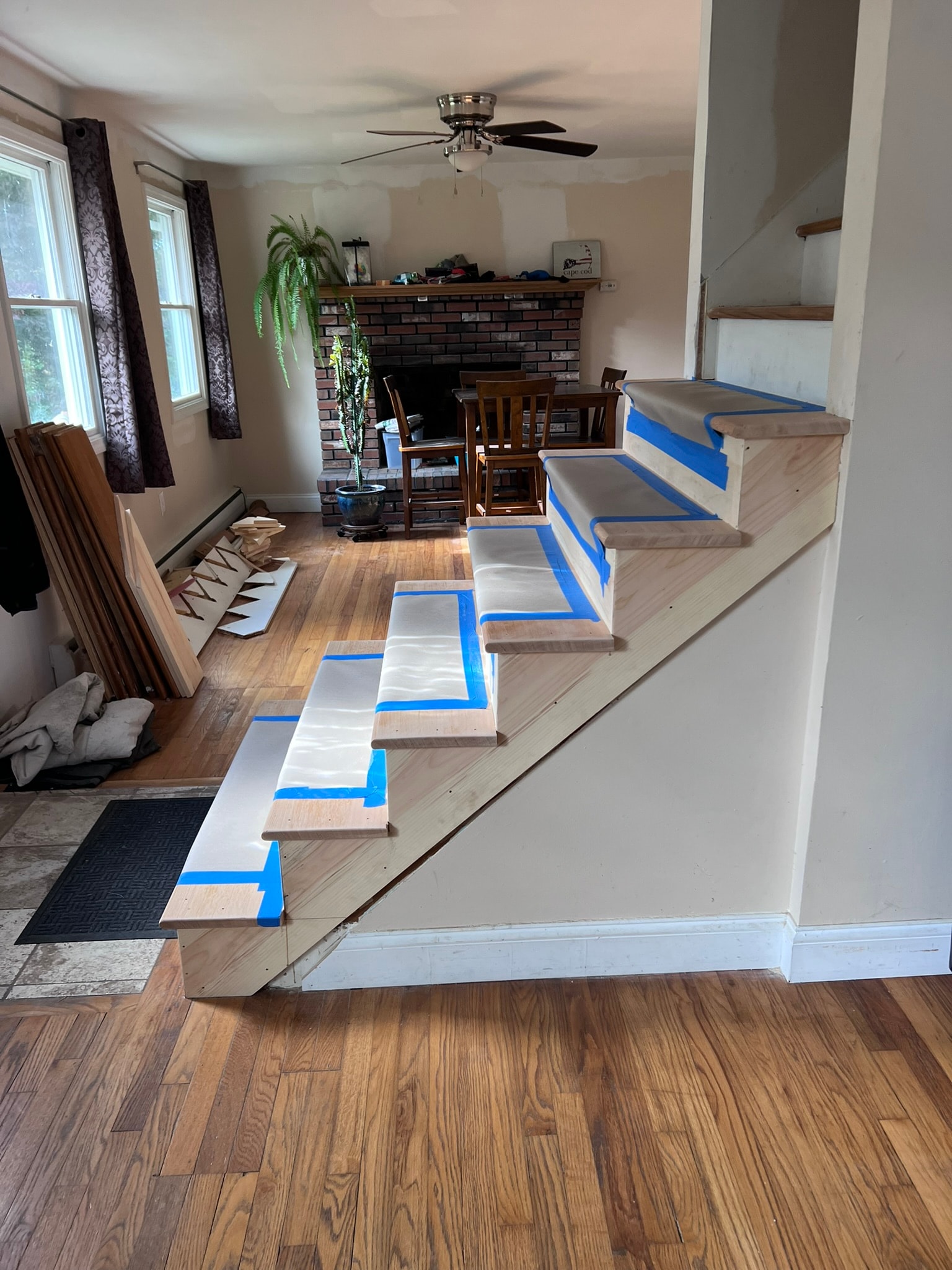 Custom staircase renovation — wall removed, open side exposed with new treads protected during construction