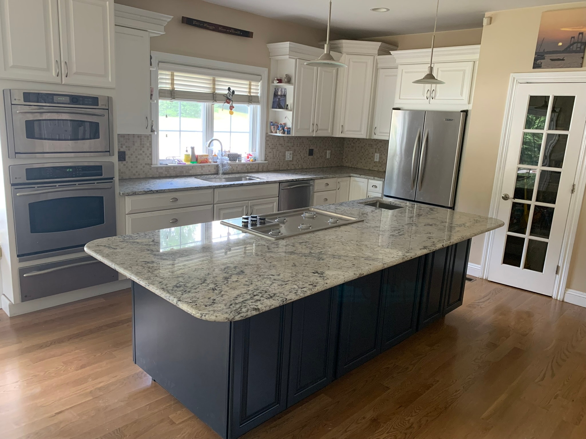 Completed kitchen renovation — new navy island with granite countertop, white raised-panel cabinetry, and new white oak hardwood floors, Eastern Connecticut