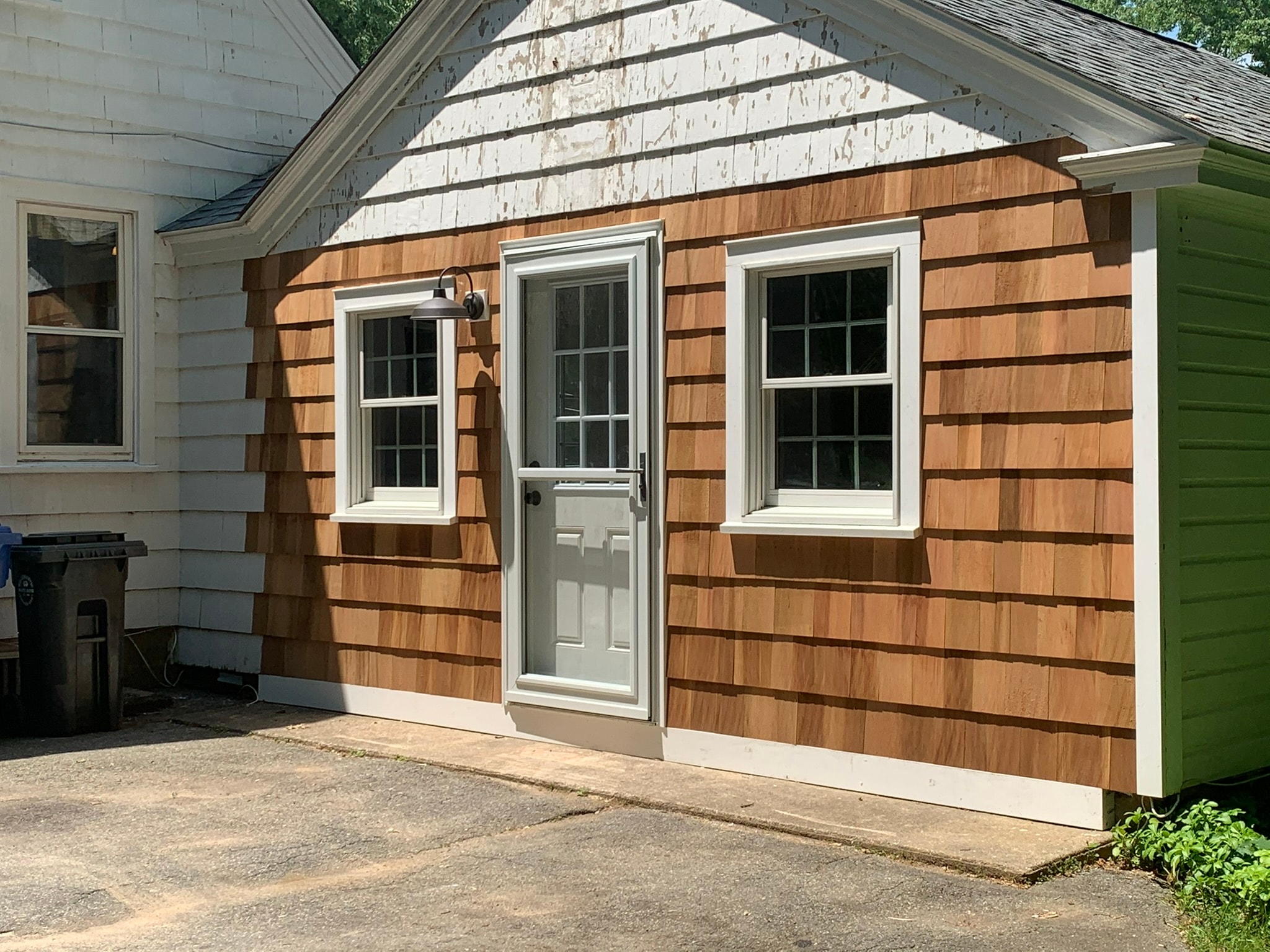 Converted garage exterior — new cedar shake siding, salvaged windows, and new entry door