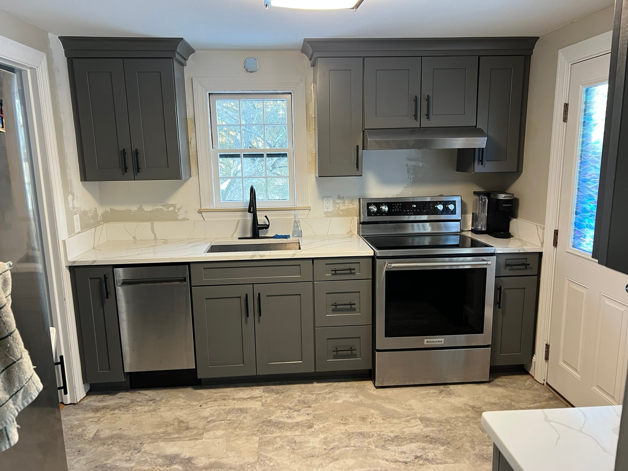 Dark gray shaker upper and lower cabinet run with calacatta quartz countertop and backsplash, matte black hardware — kitchen remodel in progress Eastern Connecticut