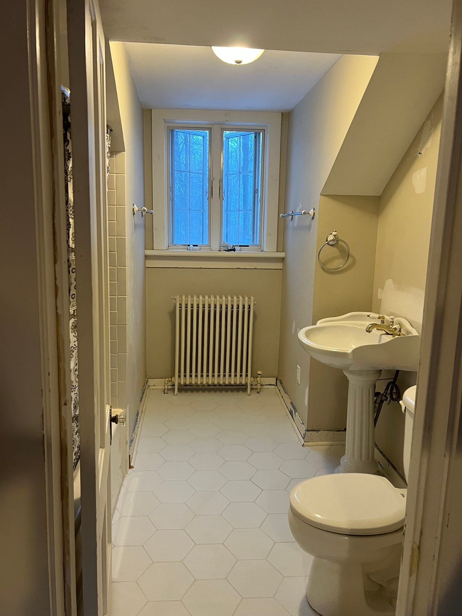 Before — original dated bathroom with pedestal sink, old hex floor, yellow walls, and radiator — Eastern Connecticut