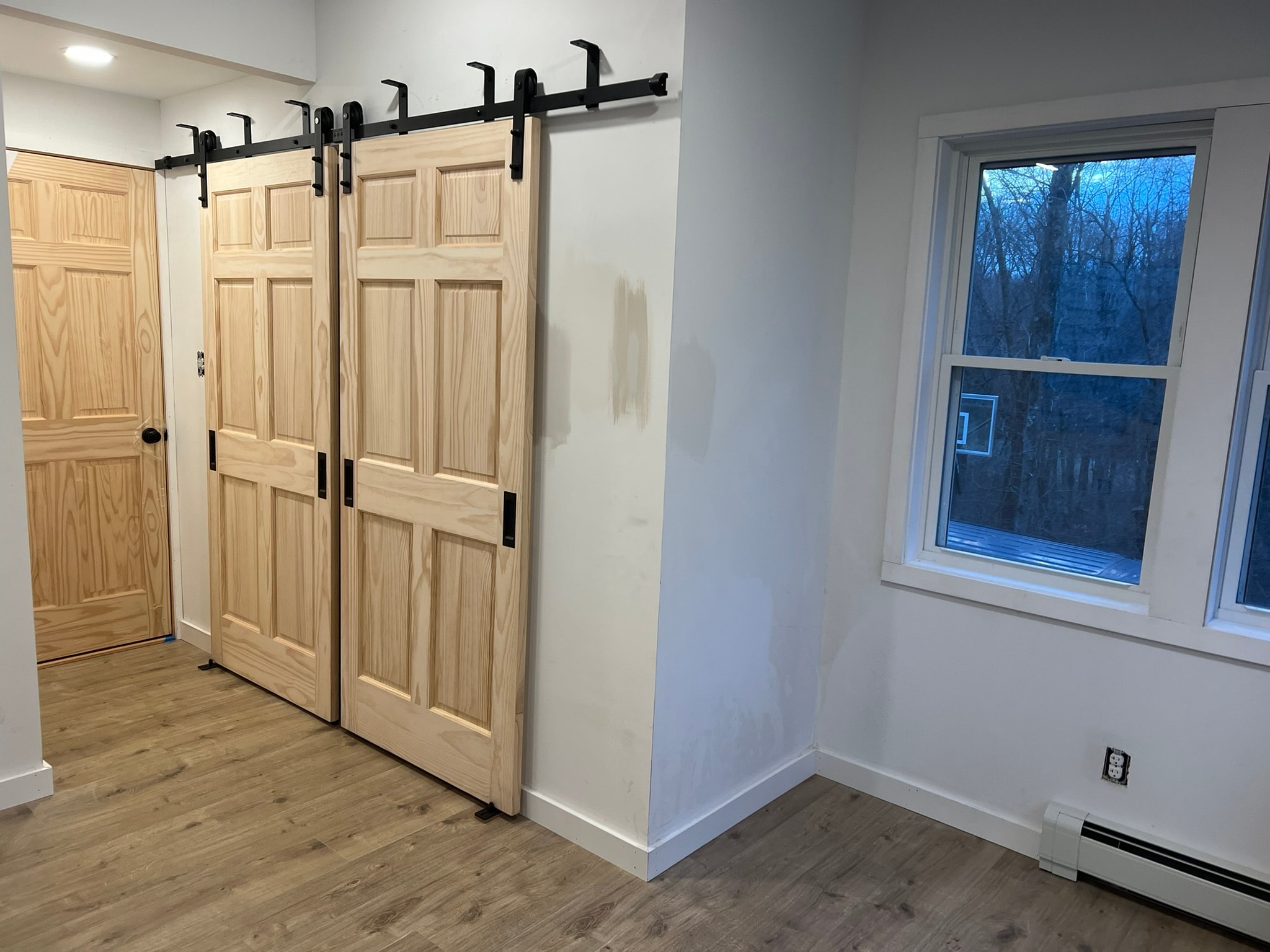 3-season porch conversion master bedroom — double sliding pine barn doors on black hardware, LVP flooring, new baseboard and trim, Eastern Connecticut