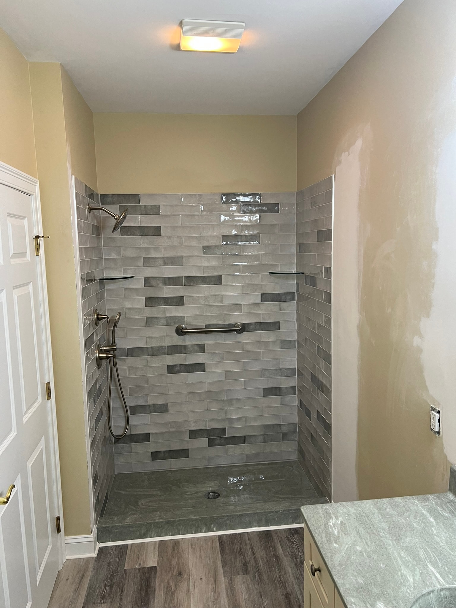 New tiled walk-in shower with gray subway tile surround, marble floor pan, and brushed nickel fixtures — bathroom renovation Eastern Connecticut