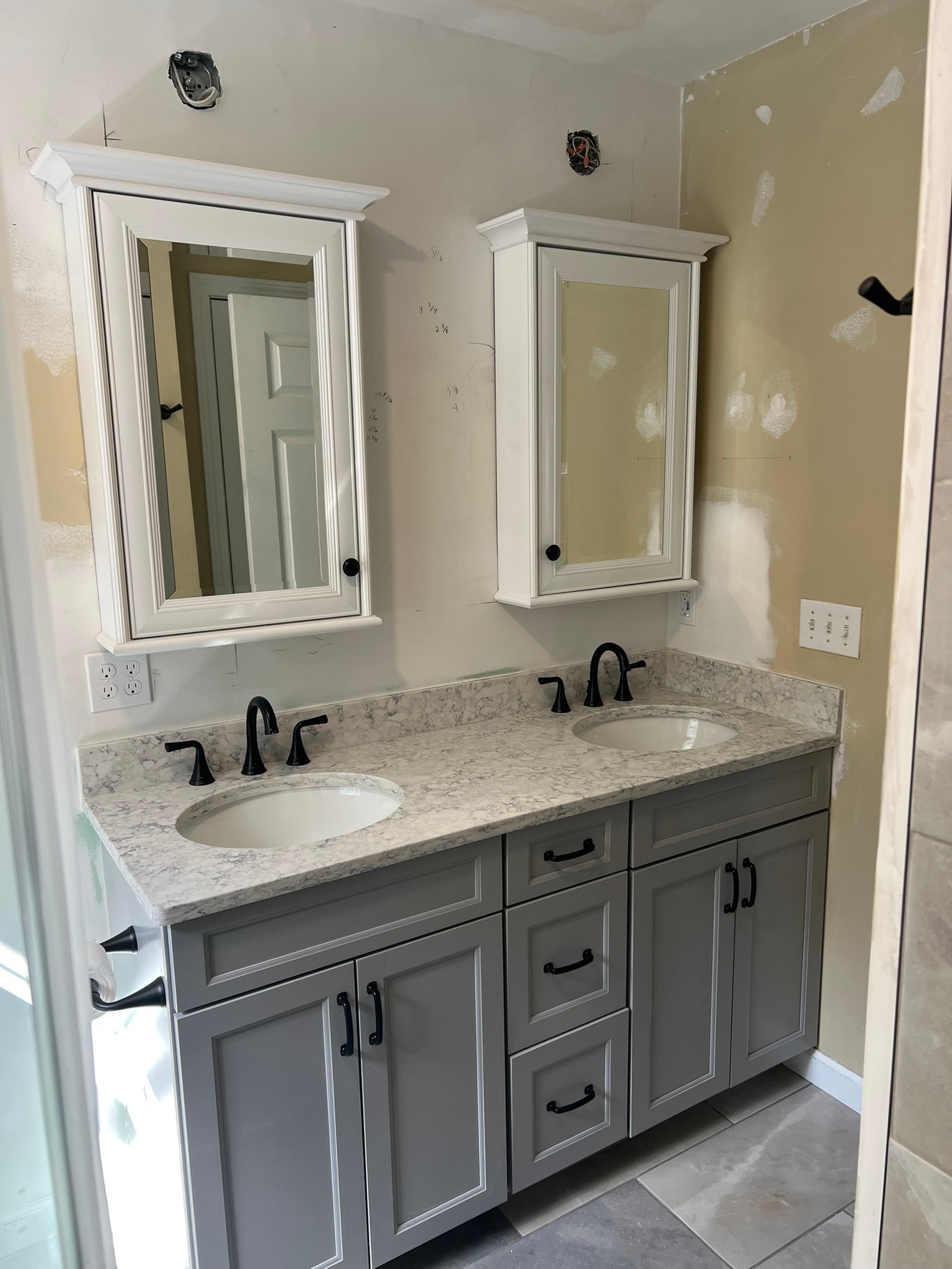 New gray shaker dual vanity with granite countertop, dual undermount sinks, black faucets, and two white crown-molded medicine cabinets
