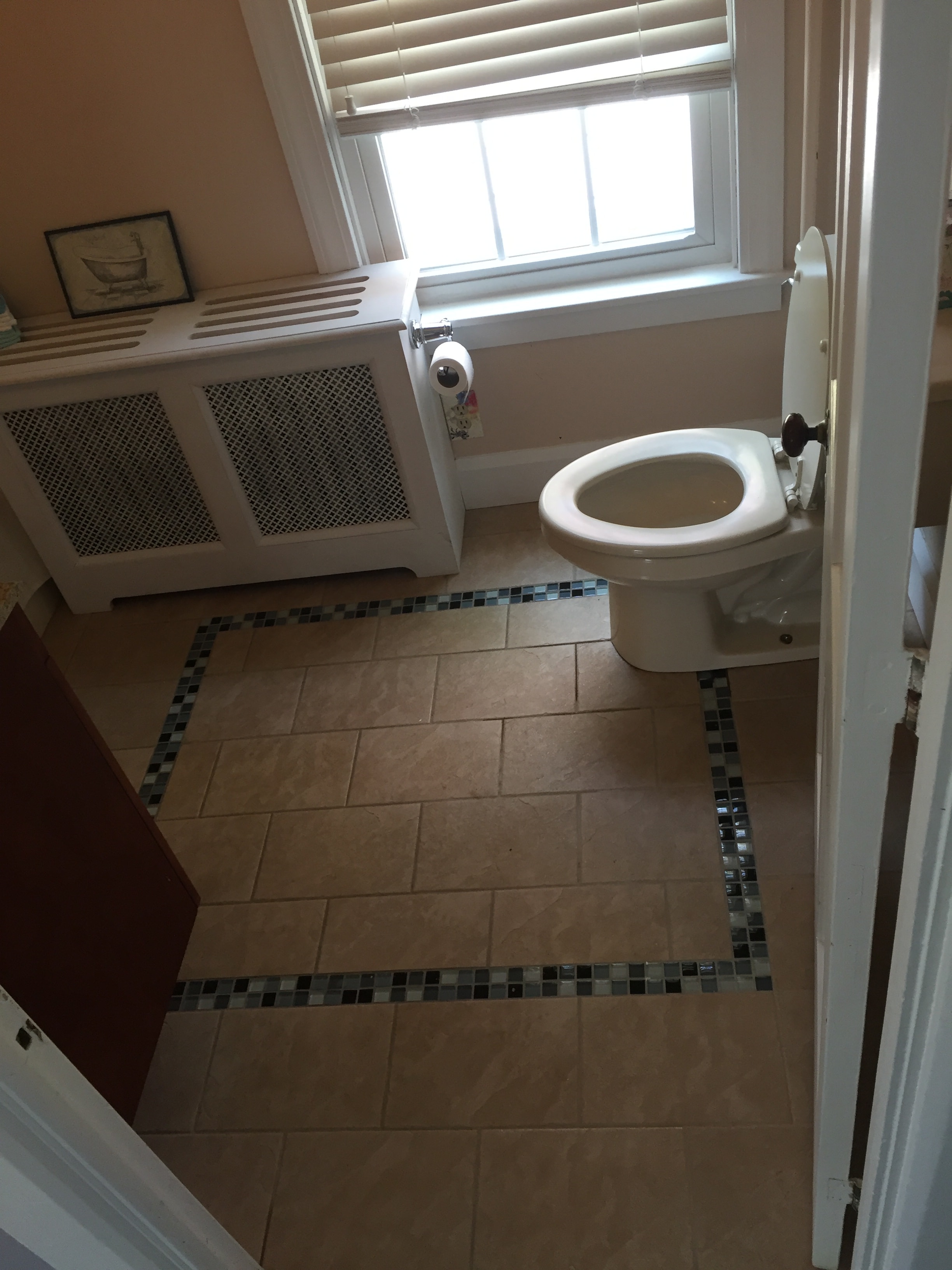 Bathroom tile floor with decorative mosaic glass border inlay