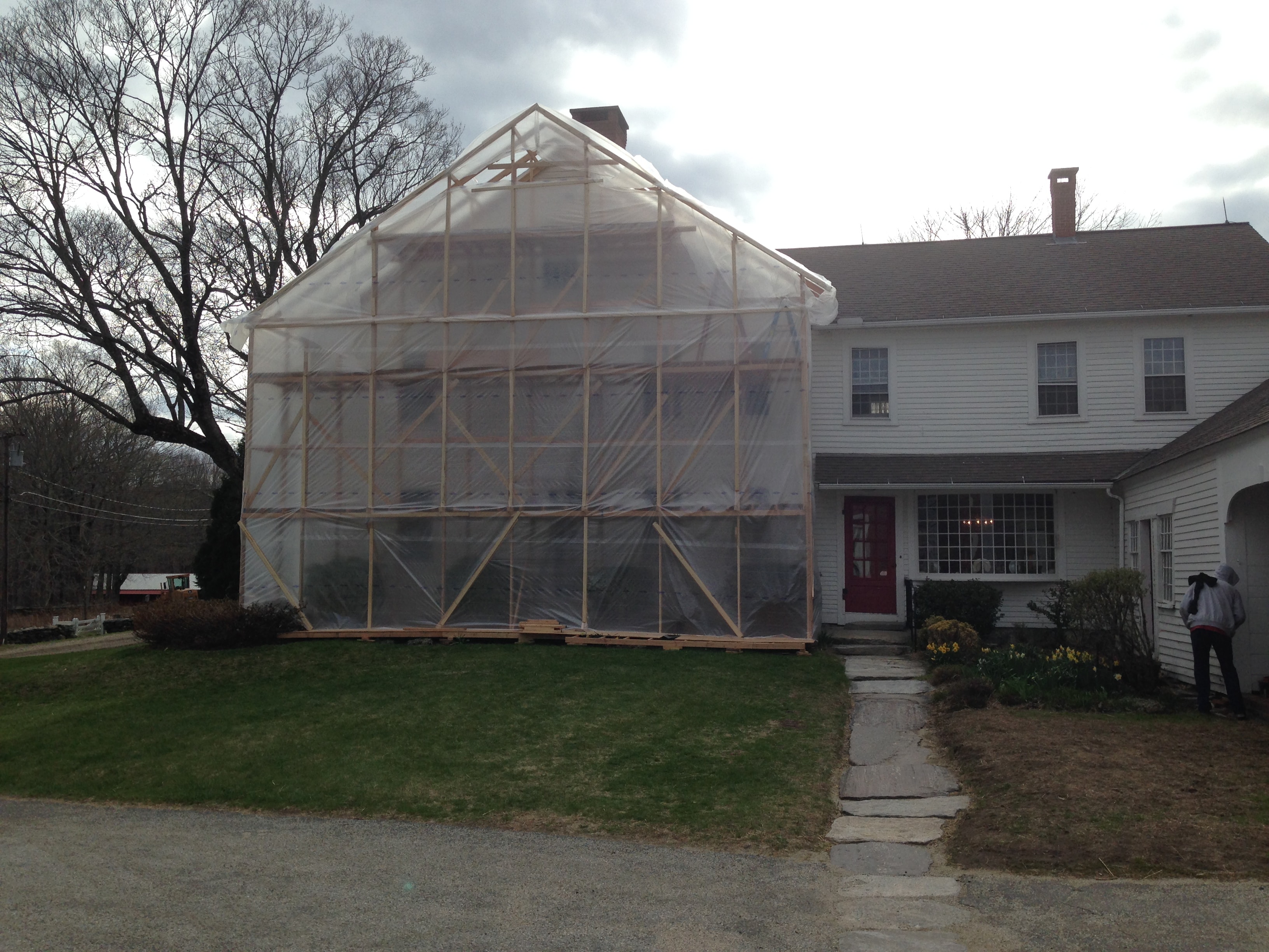 Gable end wrapped in plastic sheeting during farmhouse restoration
